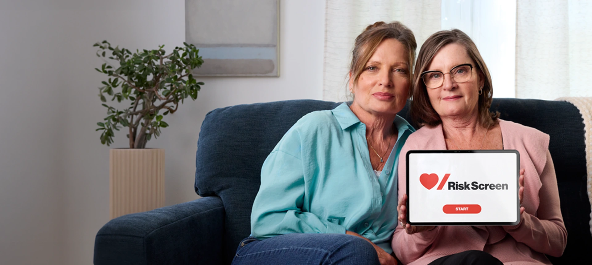 Sisters Sharon and Carolyn holding a tablet with Risk Screen tool on the screen.