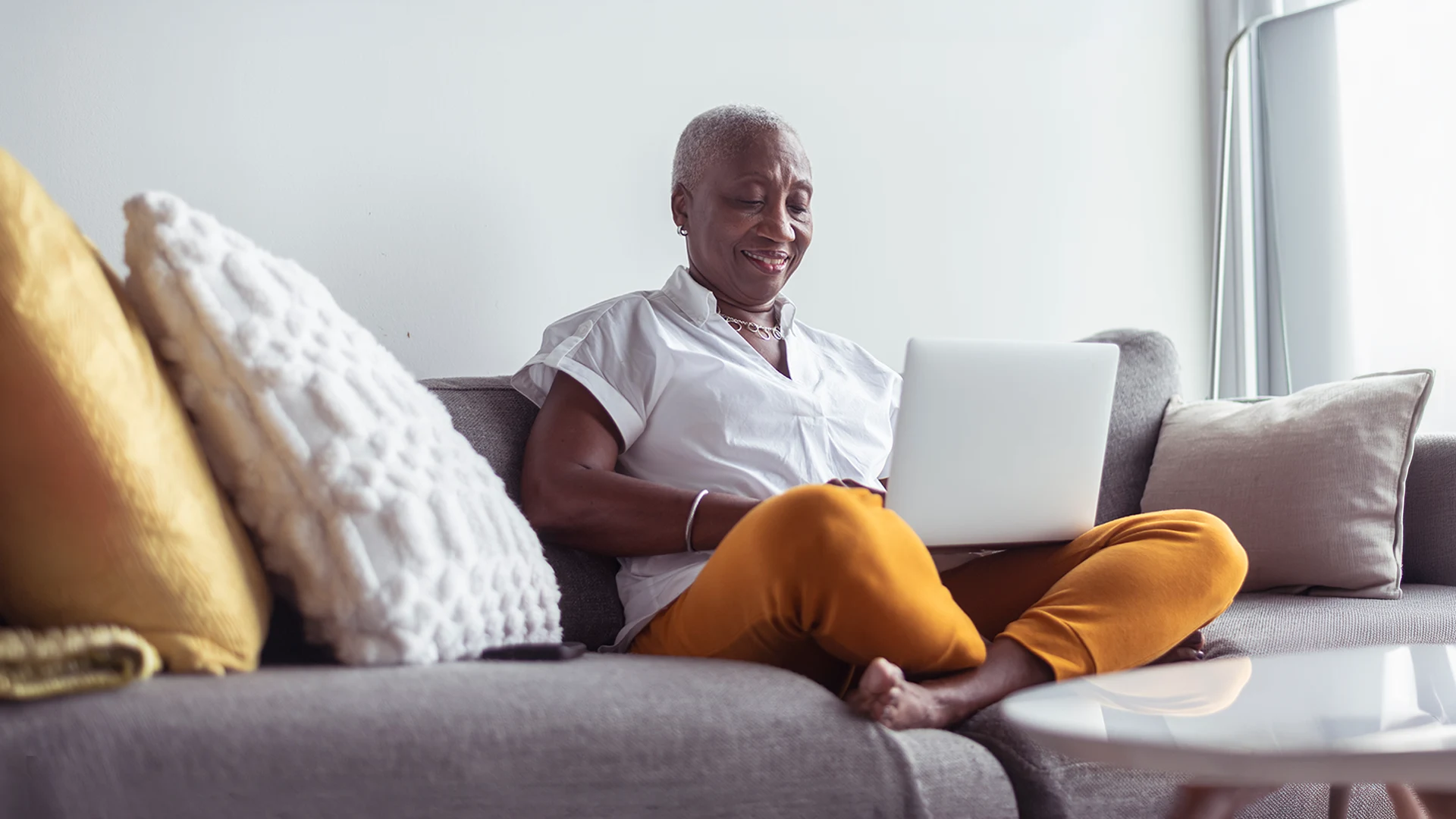 Senior woman using laptop while sitting on couch.