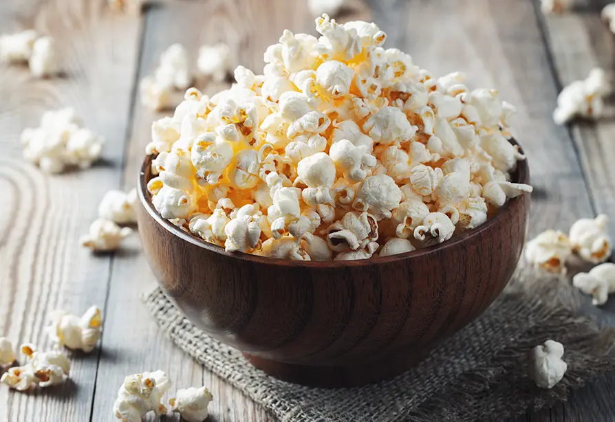 Bowl filled with popcorn on a wooden table.