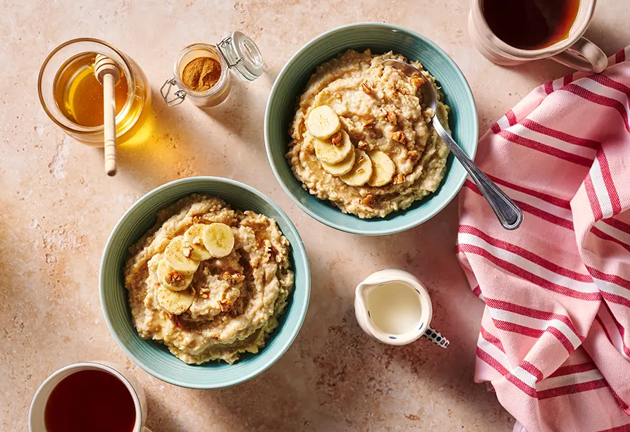 Banana millet breakfast porridge in blue bowls with banana slices on top.