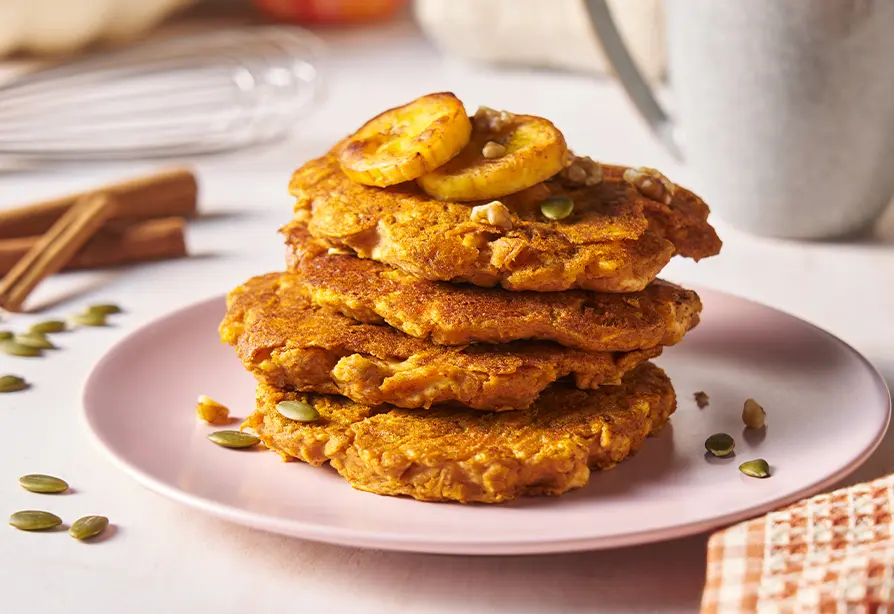Stack of plantain and pumpkin pancakes on a white plate. 