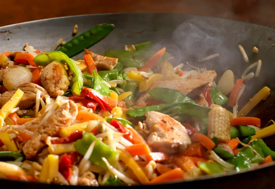 Chicken and vegetable stir fry chopped in a black wok