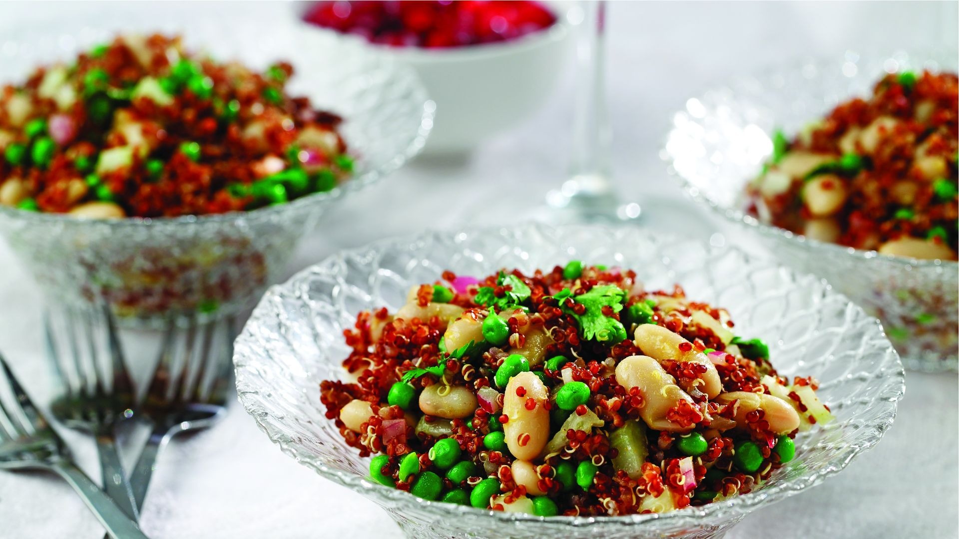 Glass bowls filled with quinoa, cannellini beans, peas and cilantro