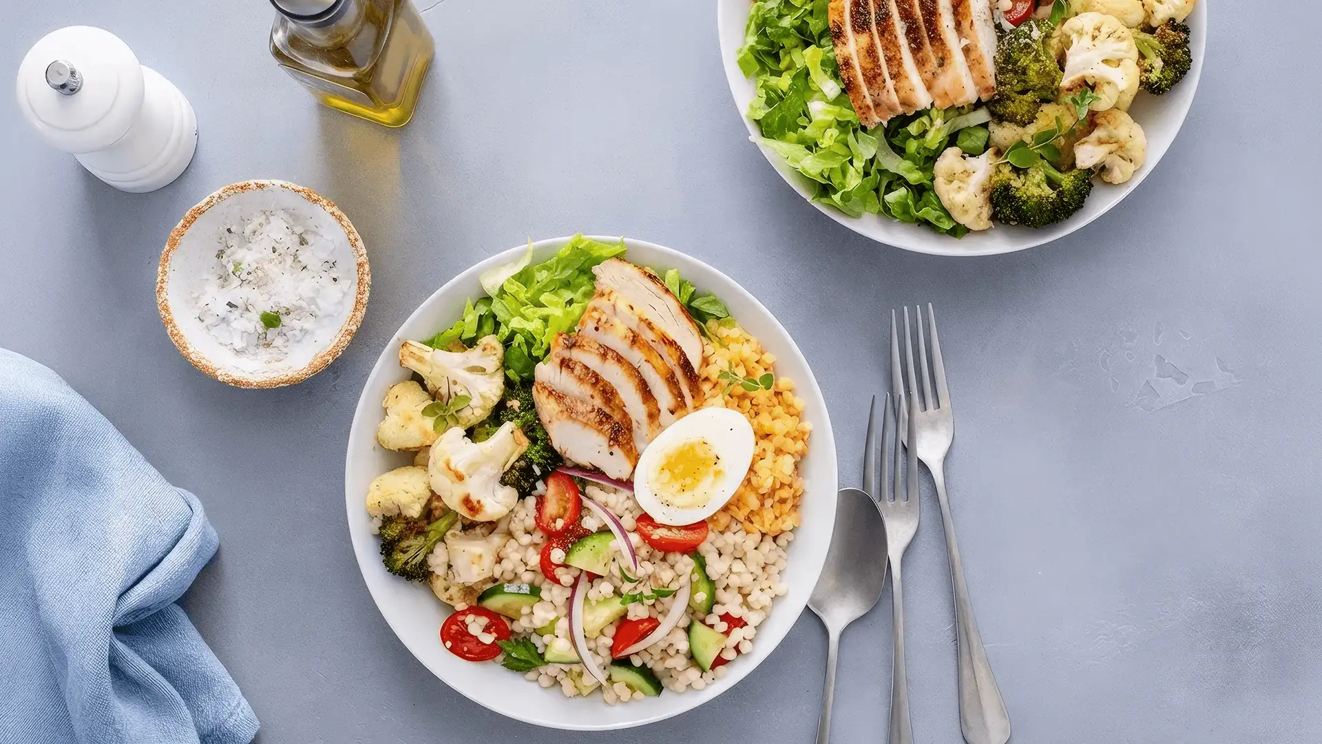 Healthy lunch bowl with grilled chicken, roasted vegetables, fresh lettuce, cooked lentils, couscous salad and hard boiled egg