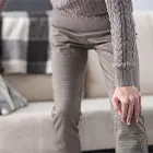 Person getting up from a couch, holding their knee
