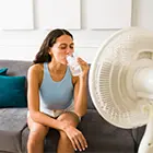 A woman cooling down in front of a fan with ice water