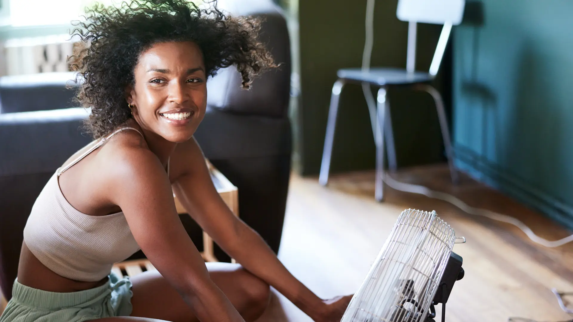 Woman sitting indoors in front of a fan