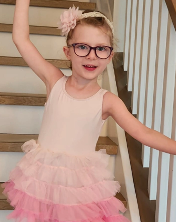 Charlotte at home, dancing on their stairway.