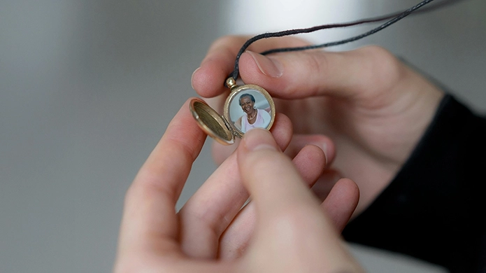 Close up of hands holding an open locket with a photo of a loved one inside