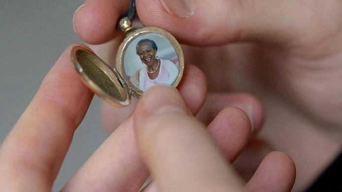 Close up of hands holding an open locket with a photo of a loved one inside