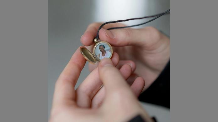 Close up of hands holding an open locket with a photo of a loved one inside