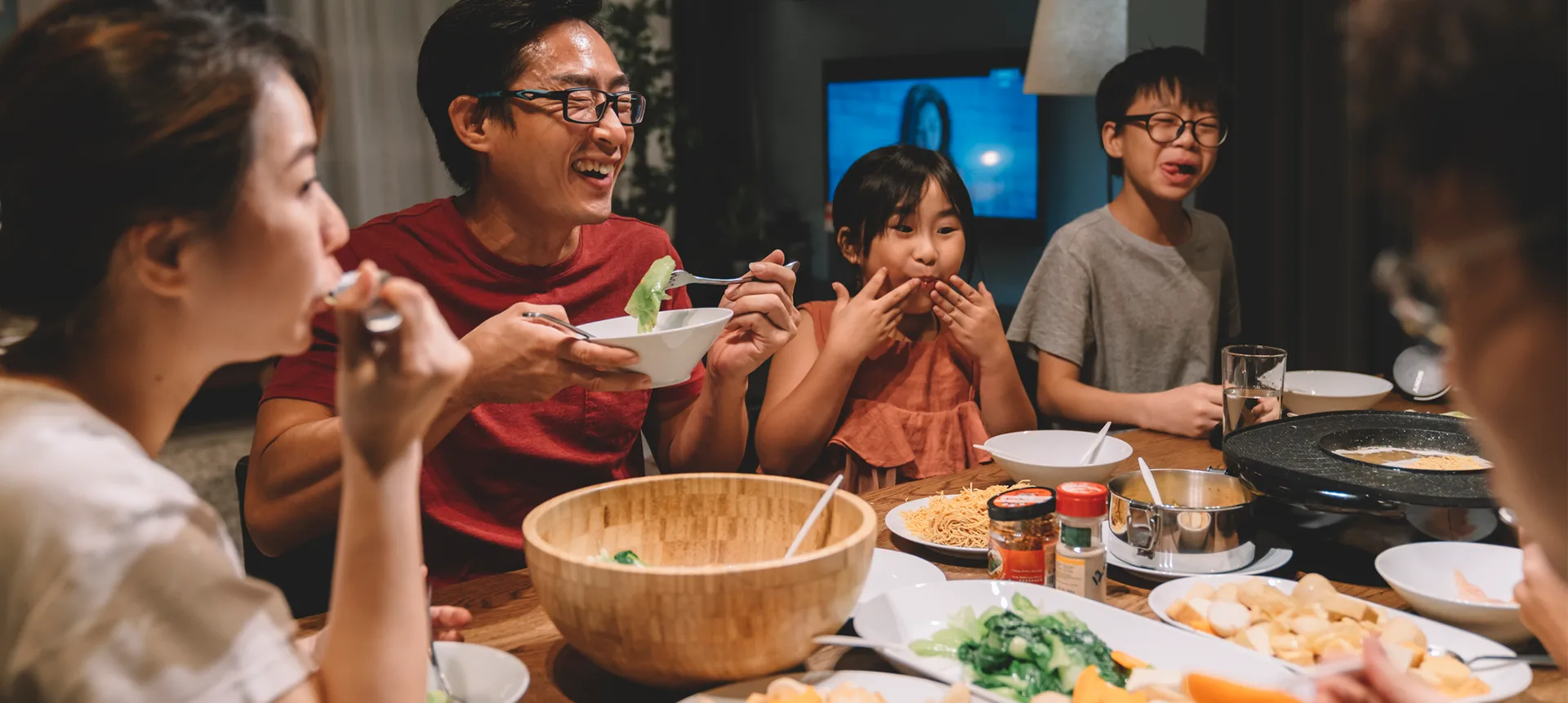 A family gathers around a dining table sharing a meal together. 