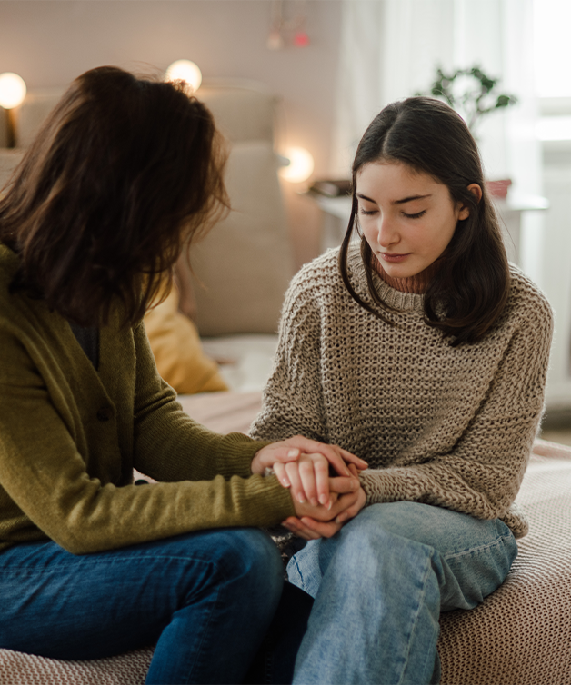 A teenage girl being comforted by her mother.