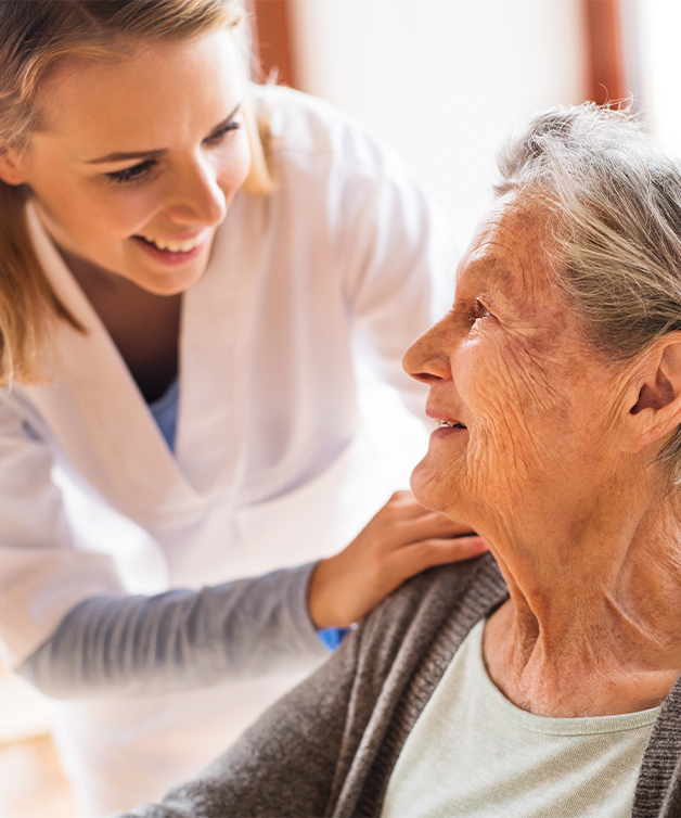 A nurse checks in on a senior person on a wheelchair.