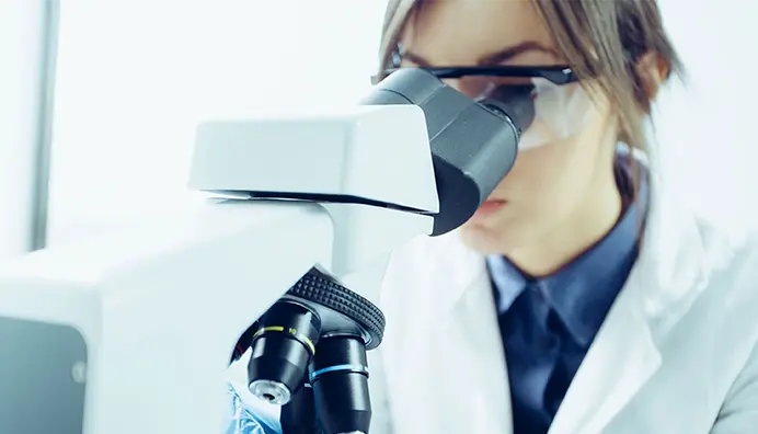 A female researcher looks into a microscope