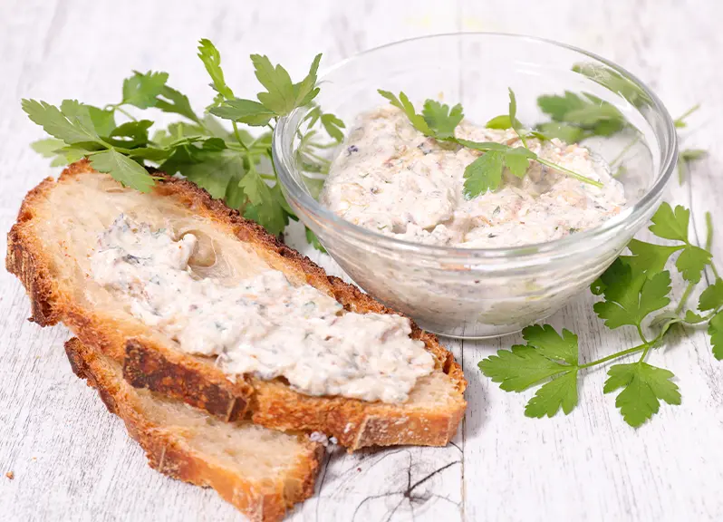 Goat cheese mint bean spread in a glass bowl with toasted bread on the side