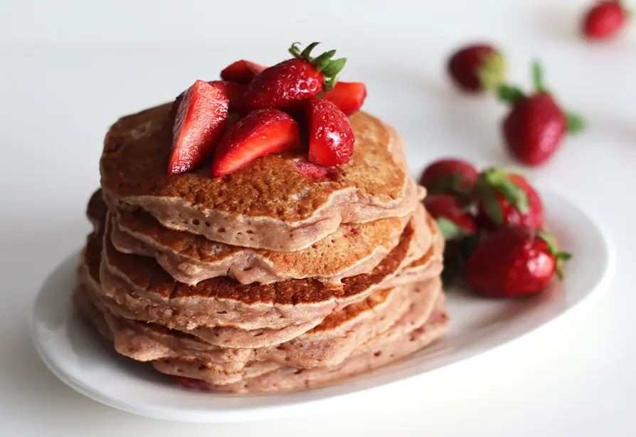 A stack of strawberry pancakes on a plate