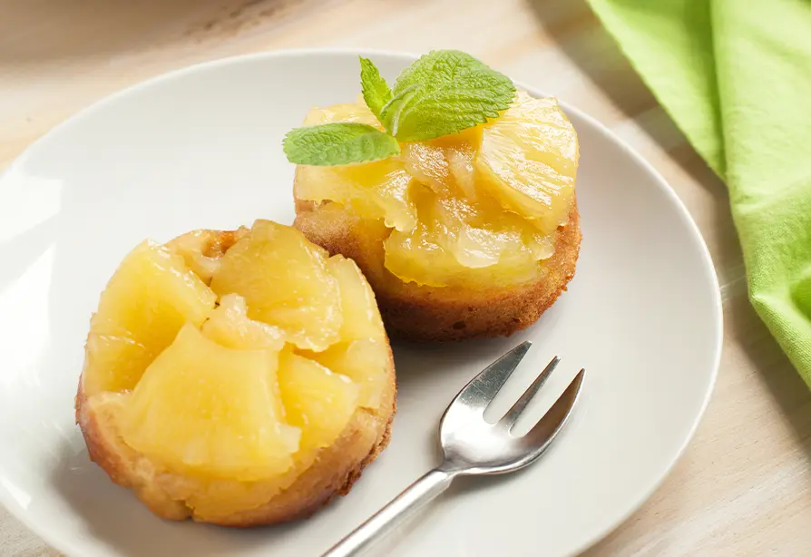 Two pineapple quinoa cakes on a white plate with a fork. 