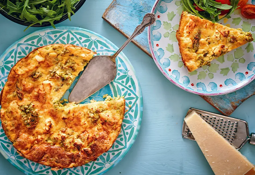 Golden salmon frittata with a serving spatula on a blue patterned plate. 