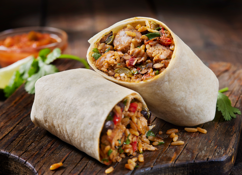 Two stuffed burritos cut open on a wooden board. 