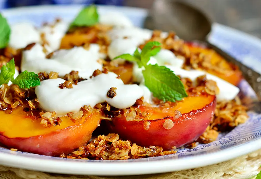 Grilled peaches on a plate with yogurt dressing on top