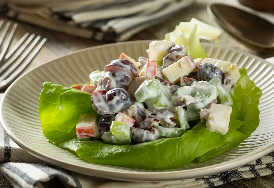 Waldorf salad with apples and berries on a bed of lettuce served on a plate