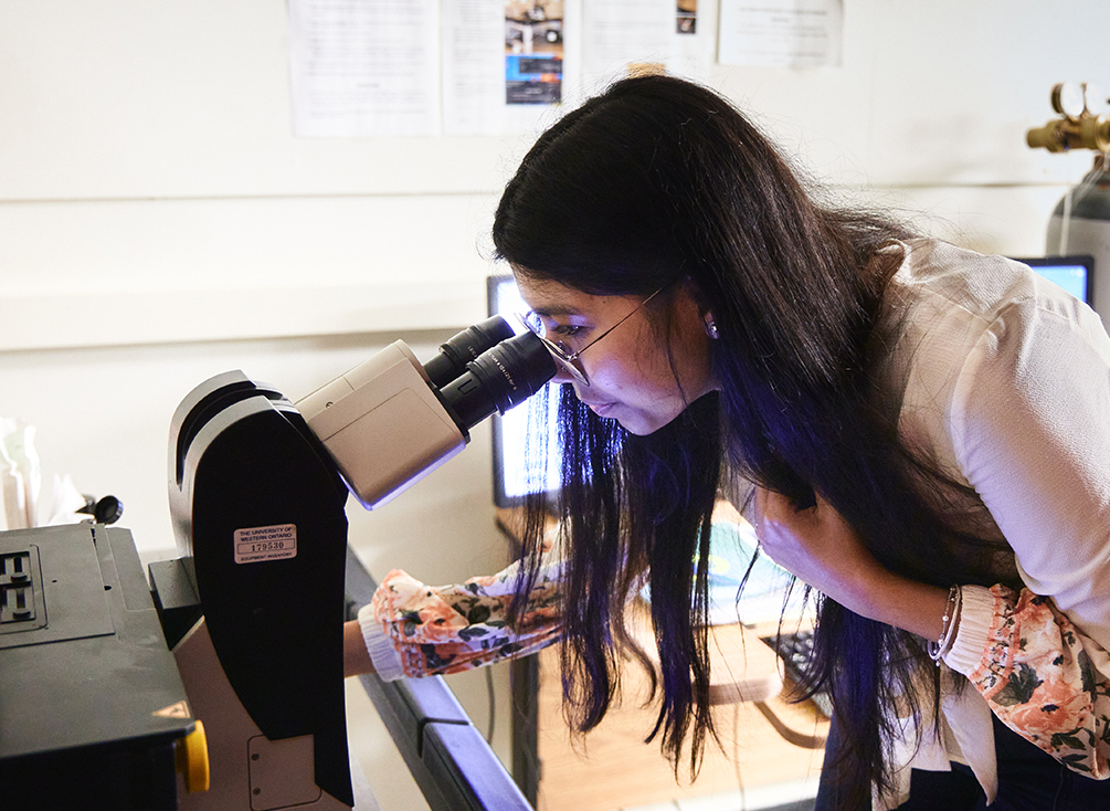 A student on Dr. Heit’s team using a microscope