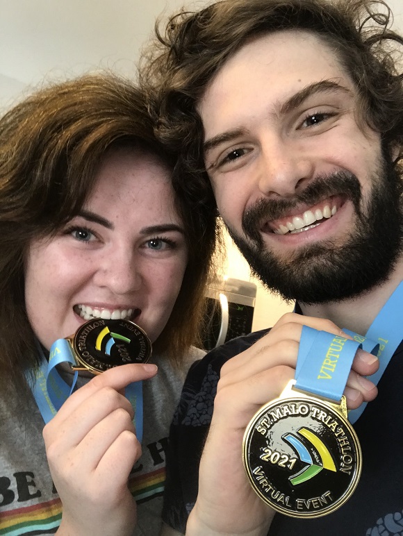 Courtney and her husband, Collin, holding medals from the triathlon event.