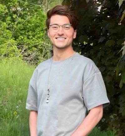 Donald poses outdoors by a tree.