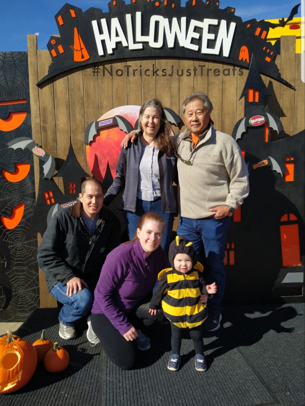 Donna and Barry with their growing family. The sign behind them reads, “Halloween: NoTricksJustTreats”