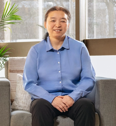 Dr. Jing Wang sitting in a grey chair