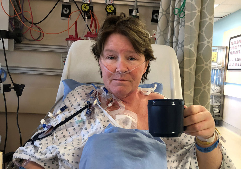Heather Evans holding a cup of tea at her hospital bed