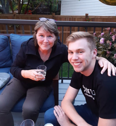 Heather with her arm around her son Skyler sitting on a porch with a glass in her hand. 