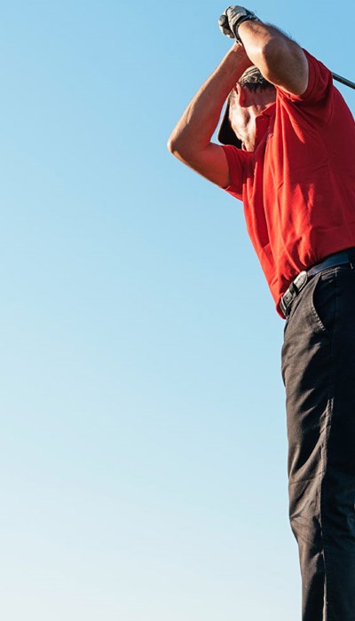 An older man prepares to swing a golf club.