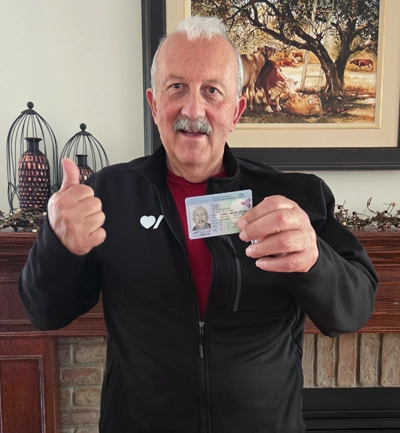 John holds up his driver’s license. 