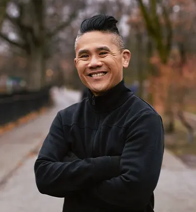 Ken Wong smiles with his arms crossed.