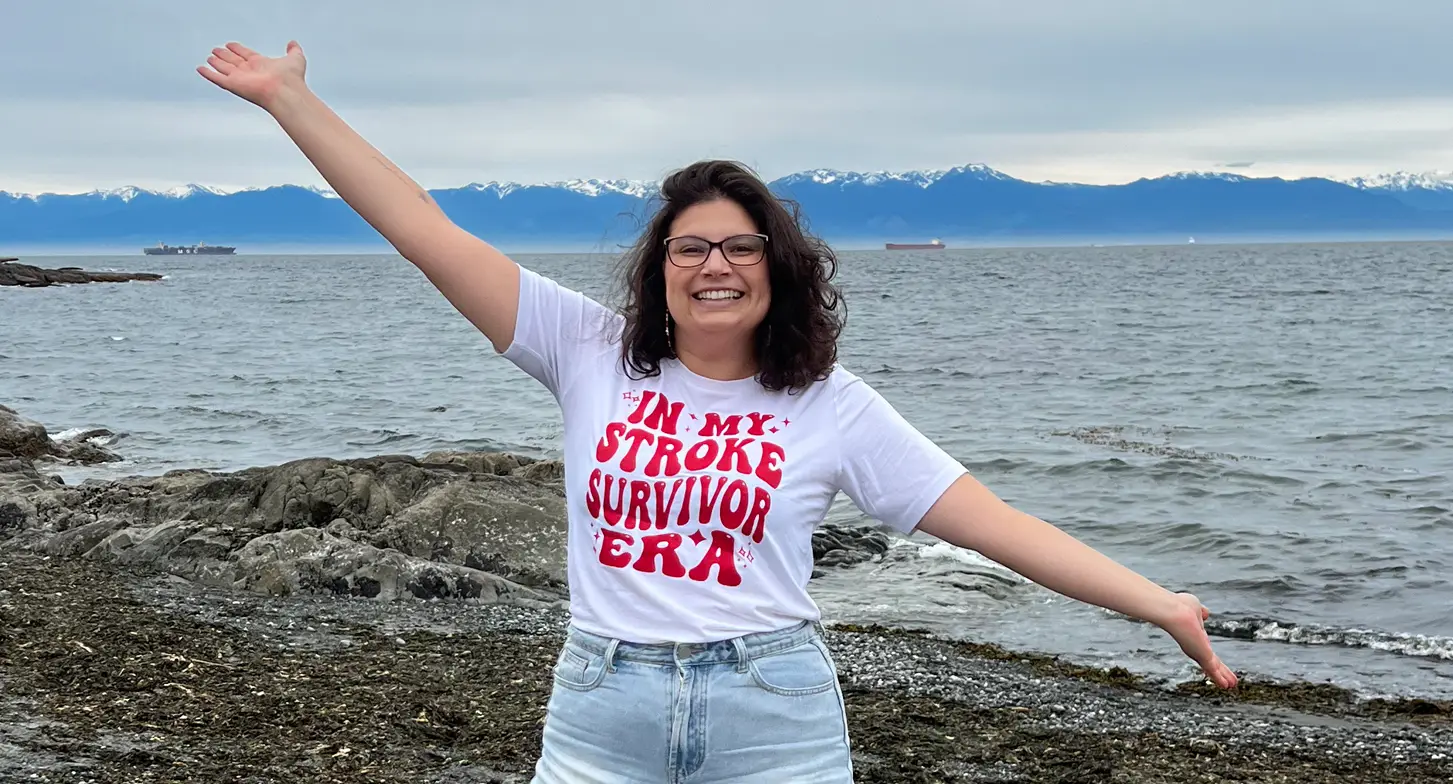 Melissa at the beach where she had a stroke. She’s wearing a shirt that says ‘in my stroke survivor era’.