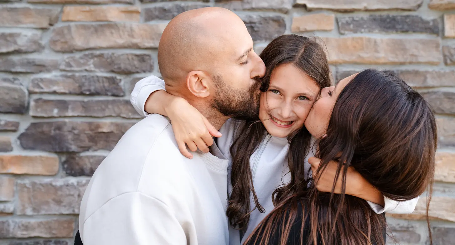 Nick Foligno and his wife, Janelle kiss their daughter, Milana.
