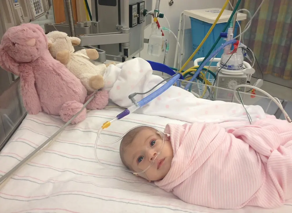 Baby Milana in a hospital bed, wrapped in a blanket.