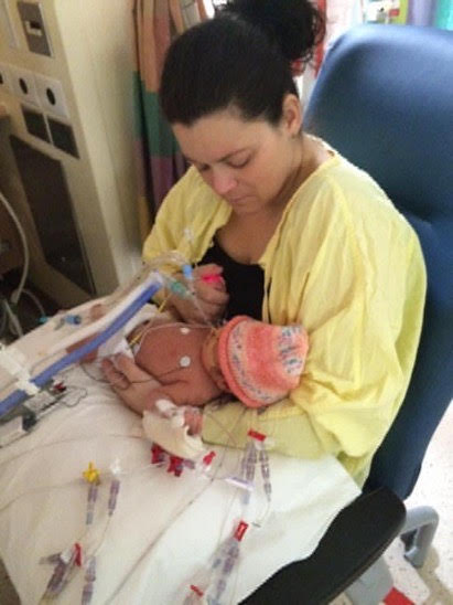 Mother Aleasha wears a hospital gown to hold baby Nora.