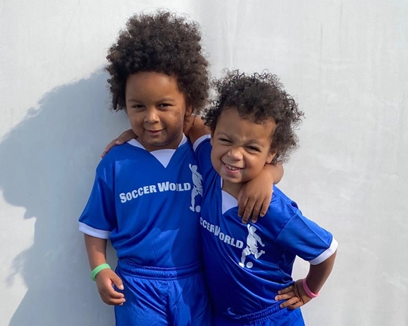 Nora (right) and her brother Koa (left) pose for a photo wearing soccer uniforms.