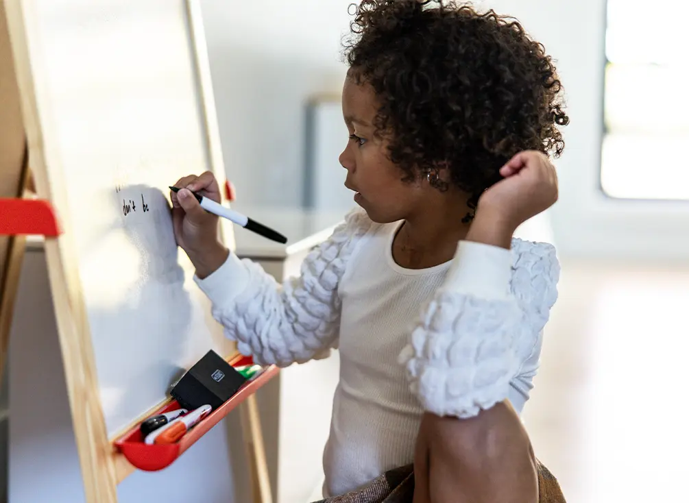 Nora Evelyn writes on a whiteboard.