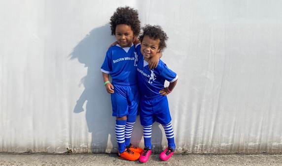 Nora (right) and her brother Koa (left) pose for a photo wearing soccer uniforms.