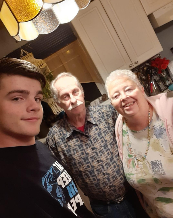A young man poses with an older man and woman.