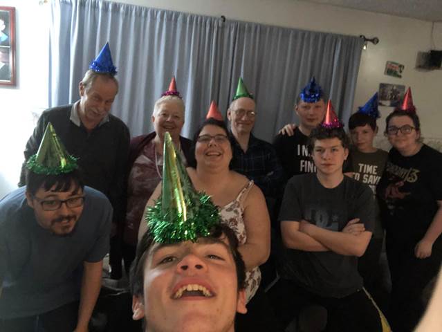 A group of family members smile wearing party hats.