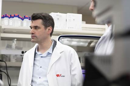Dr. Pare in a white lab coat with the Heart & Stroke logo on it 