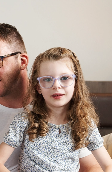 Portrait of young Charlotte sitting on her dad's lap.
