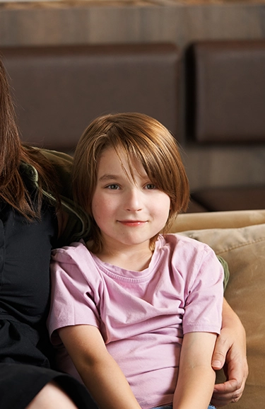 Portrait of young Logan sitting with his mom on the couch