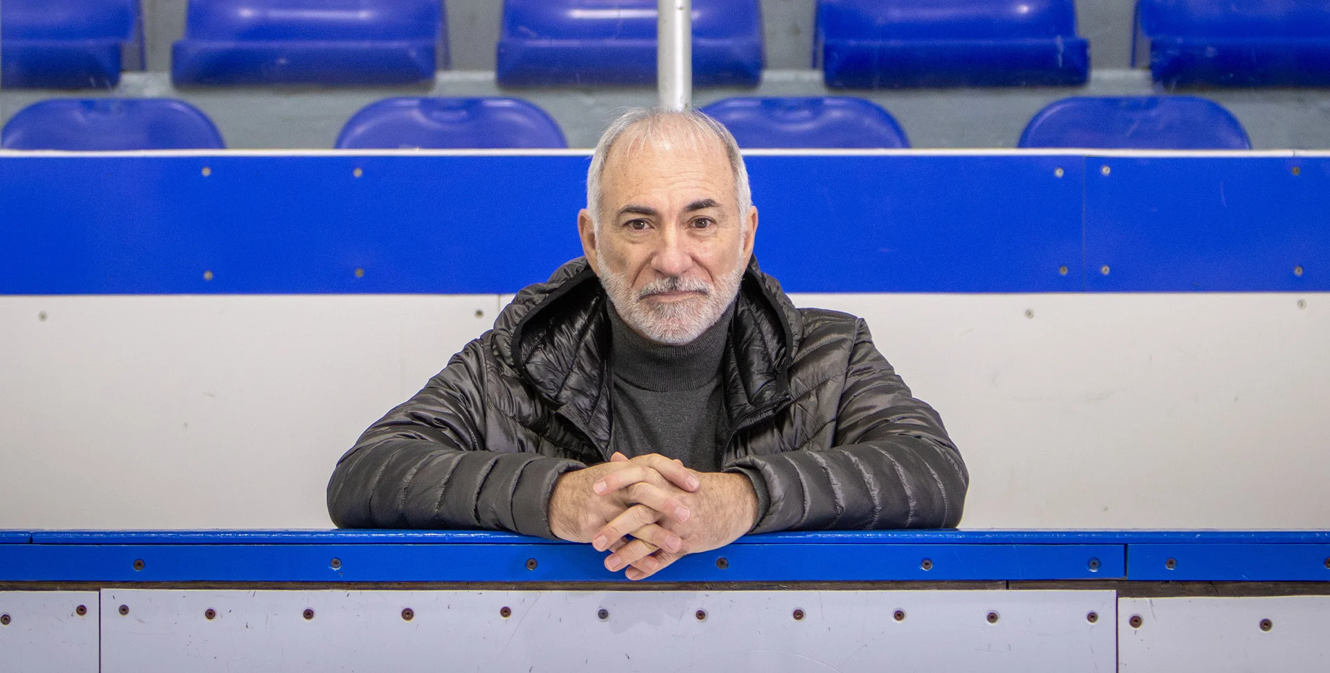 Cardiac arrest survivor Robert Marien leans on a hockey arena bench