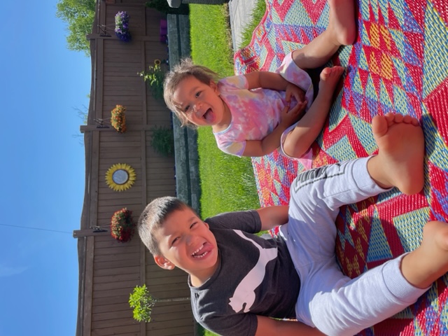 Samantha's two young children sitting outside on a blanket.